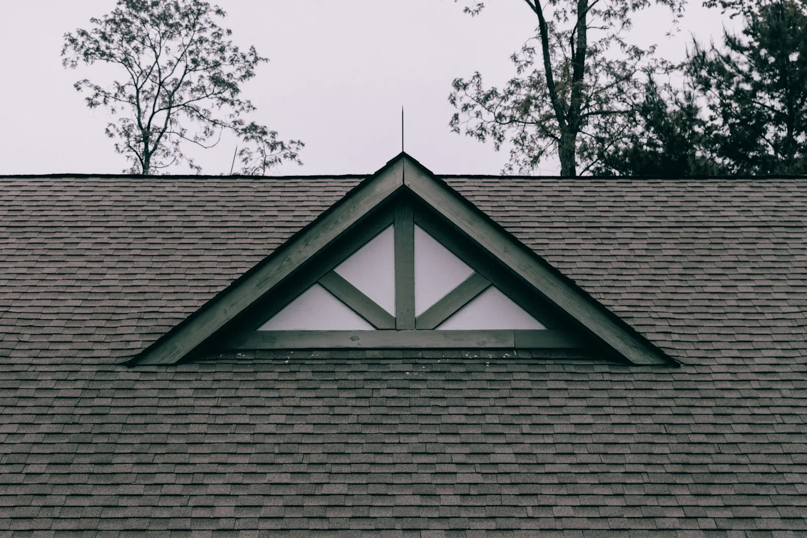 Dark asphalt shingle roof with a decorative triangular gable truss and white trim